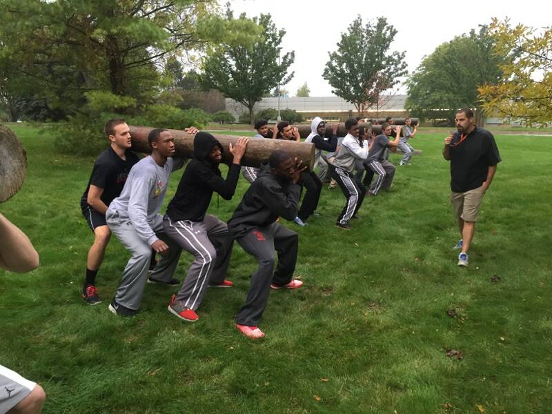 A college team lifts telephone poles together as part of a Victors Edge drill