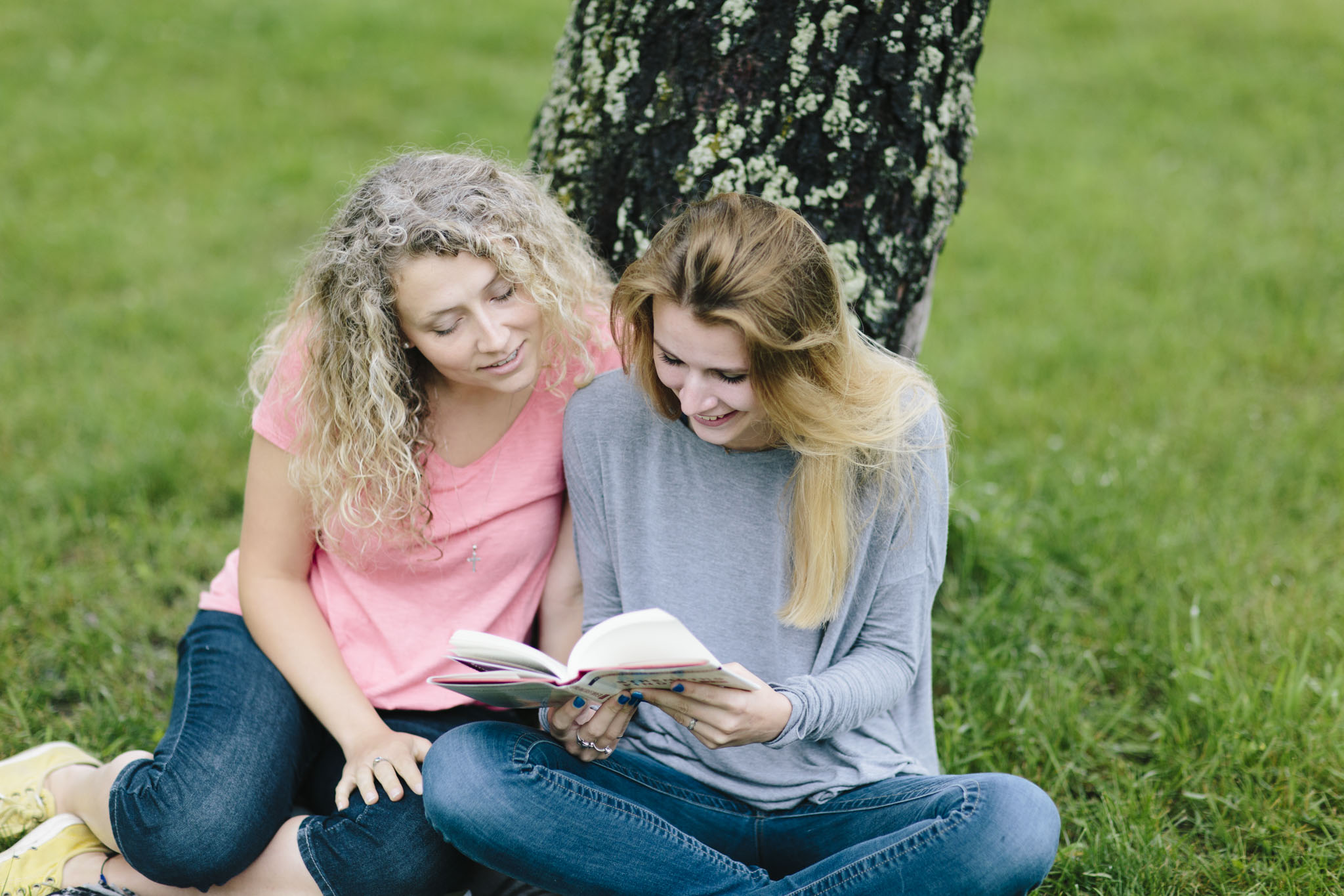 A mentor and teen sit outside and talk about a book they are reading