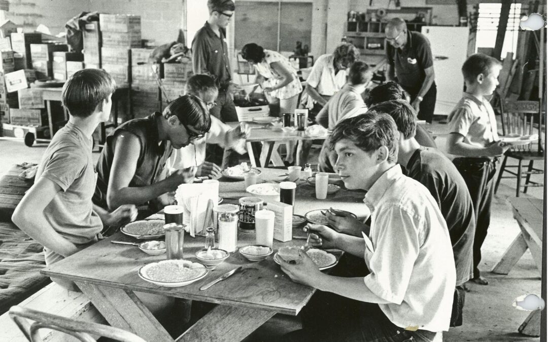 Some of the original boys of Eagle Village share a meal together at wooden tables