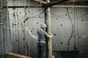 One teen holds onto the center pole of the high ropes course during a Family Challenge Weekend event