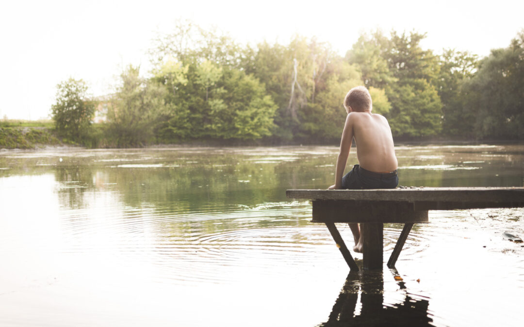 Boy sitting at the lake alone