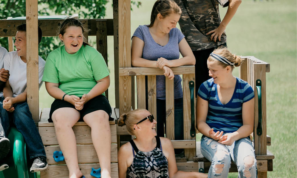 A foster care family hang out together at a playground